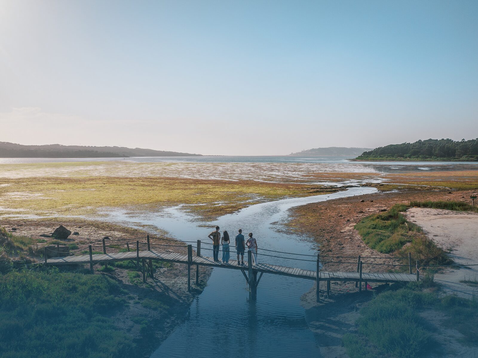 Hikers standing on a wooden bridge over the Óbidos Lagoon during the Lagoon Trail adventure.
