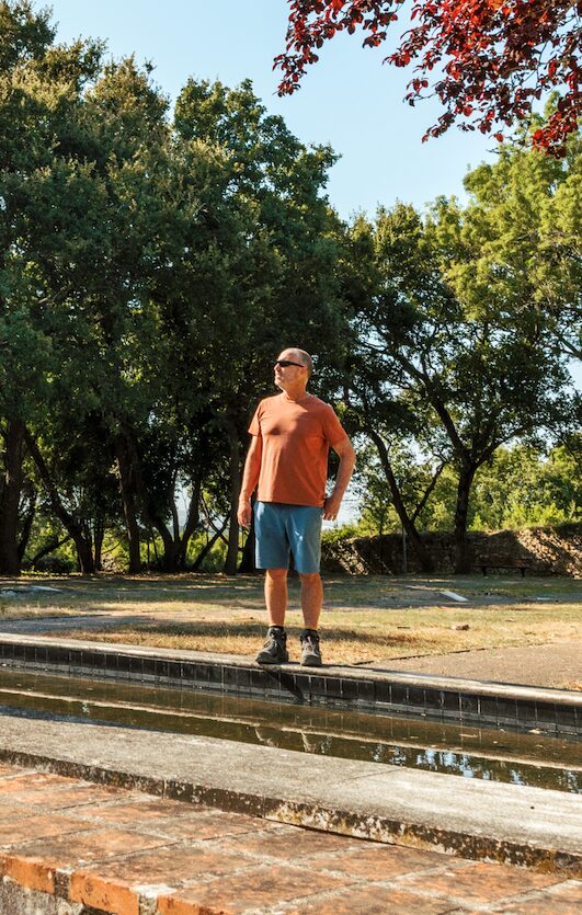 Man pausing by a peaceful water feature along one of the best hiking trails.