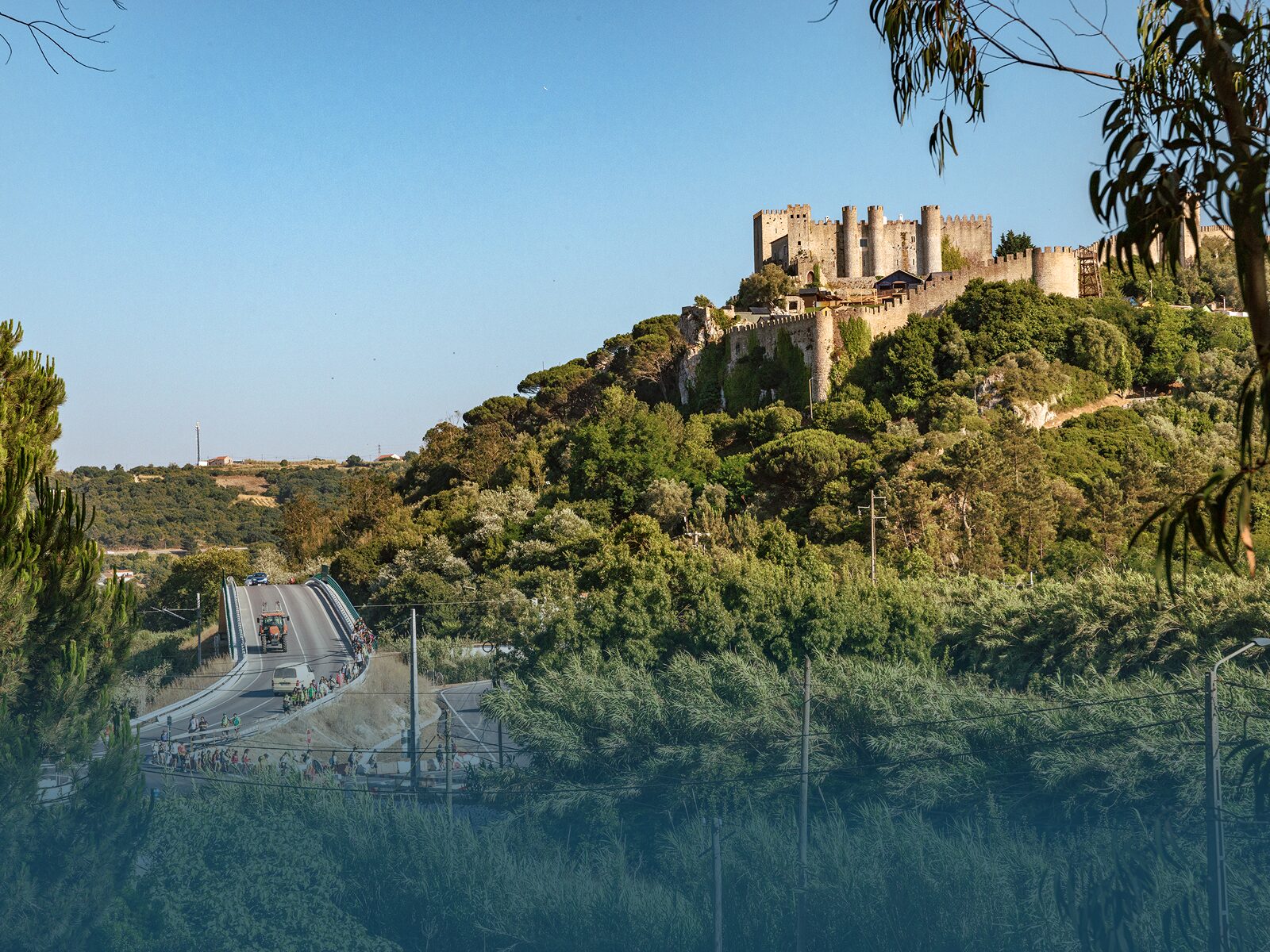 Walking group crossing bridge outside Óbidos castle surrounded by nature